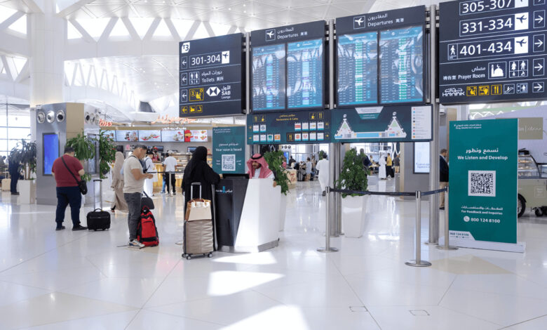 Passengers inside an airport terminal near departure information screens and check-in counters.