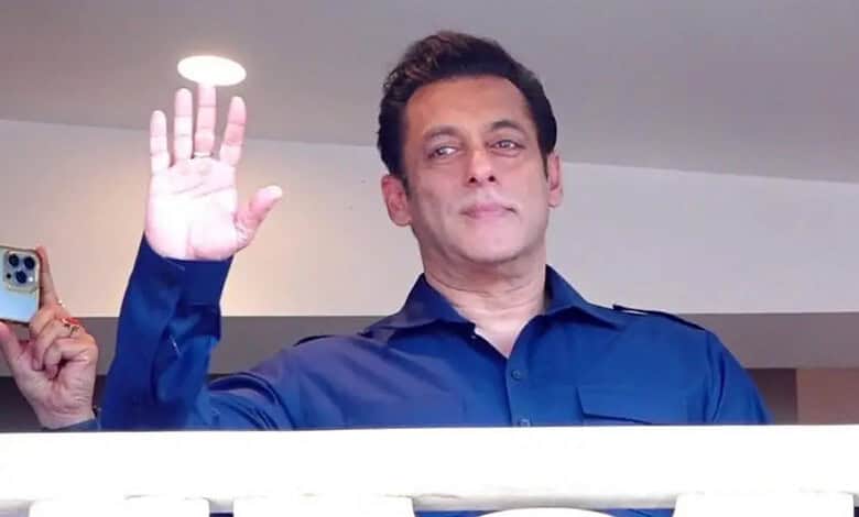 Salman Khan waving with a confident expression in a blue shirt.