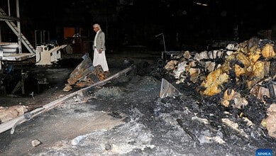 Person inspecting damage at a site with debris and burnt materials after strikes.