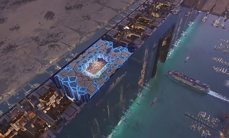 Aerial view of NEOM stadium with futuristic design and surrounding water in Saudi Arabia.