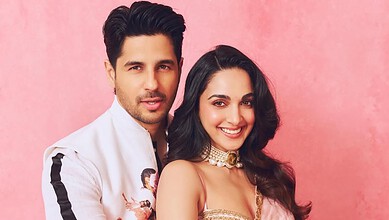 Kiara Advani and Siddharth Malhotra smiling together against a pink background.