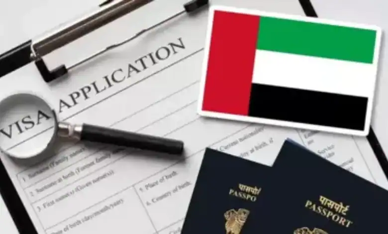 Magnifying glass over visa application form with UAE flag and passports.